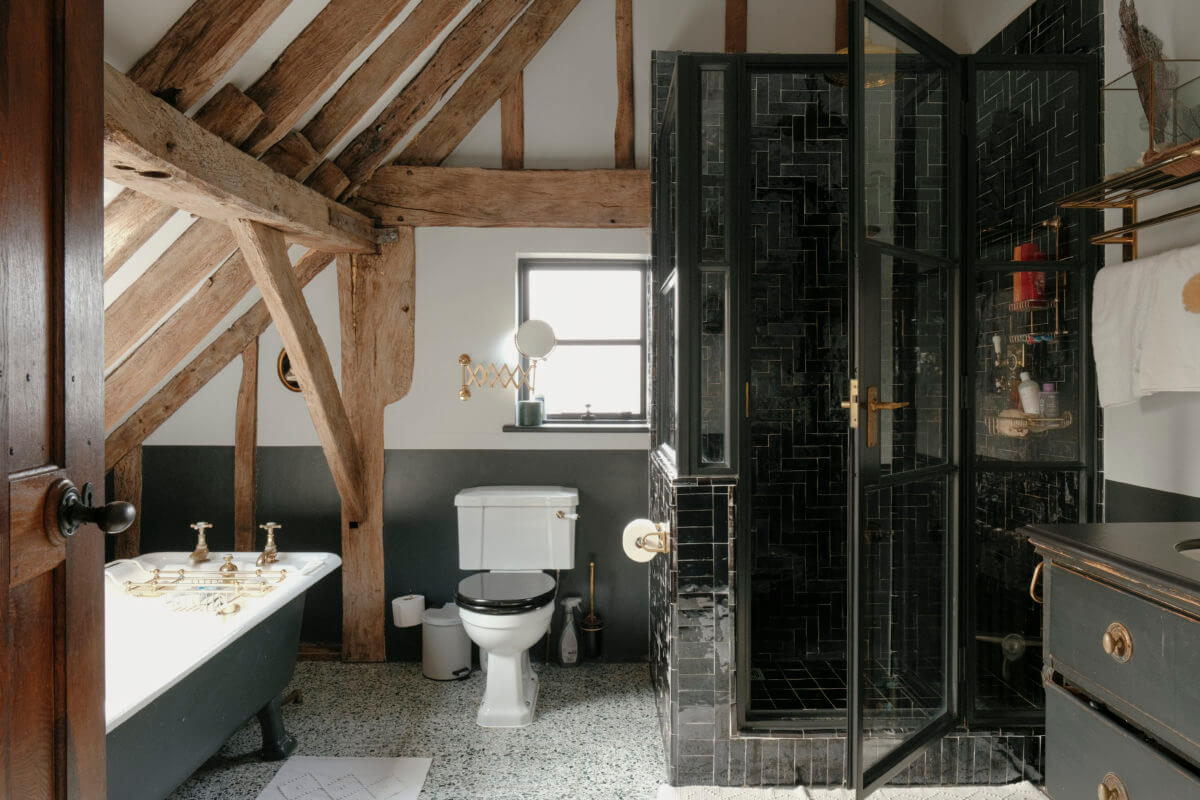 A Barn House with Vintage Decor and Exposed Beams 28 bathroom slanted ceiling with wooden beams and black tiles