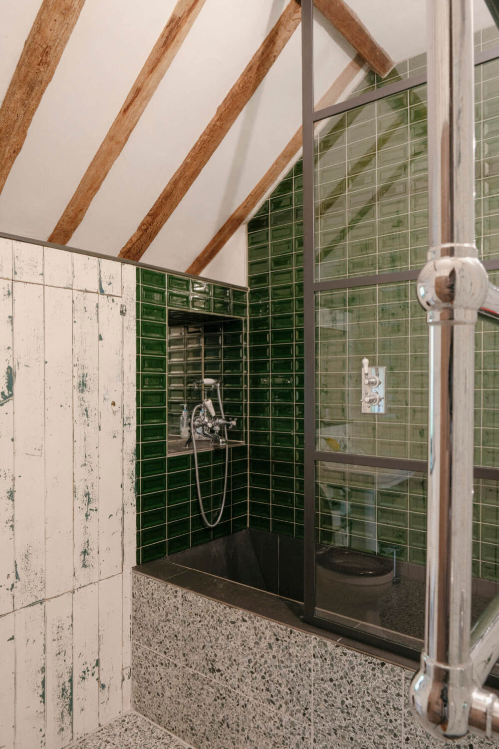 A Barn House with Vintage Decor and Exposed Beams 38 bathroom with pitched ceiling wooden beams and green tiles