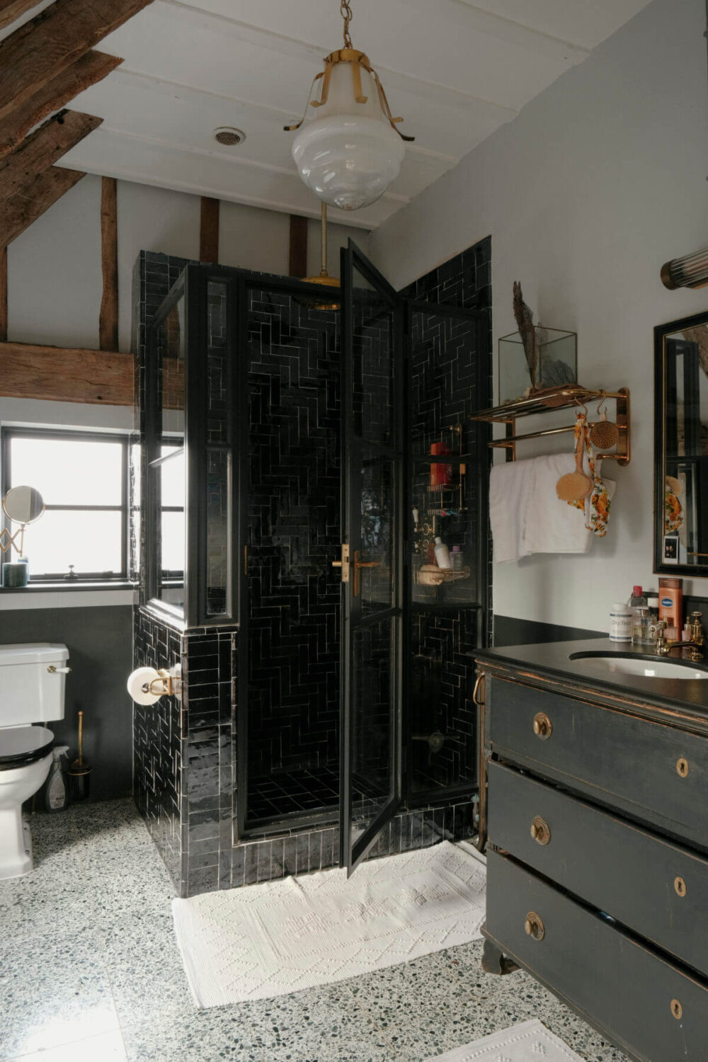 A Barn House with Vintage Decor and Exposed Beams 27 bathroom with wooden beams and black tiles in shower