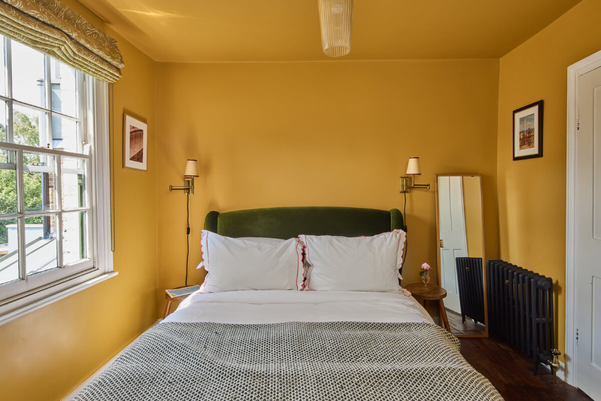 A 19th Century London Cottage with a Stunning Kitchen Extension 18 color-drenched yellow bedroom with green headboar