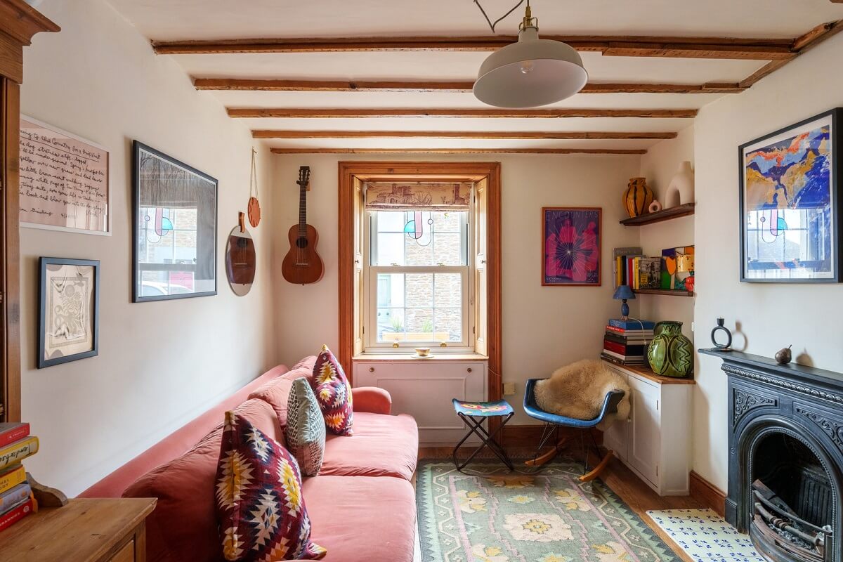 cottage living room with pink couch fireplace and exposed beams