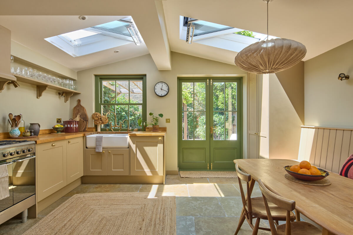 extended kitchen with large skylights stone floor green window frames