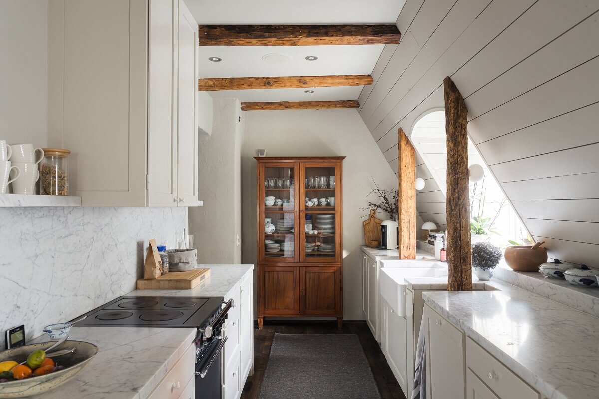 A Stylish Penthouse Apartment with Exposed Beams 11 gray galley kitchen slanted ceiling wooden beams