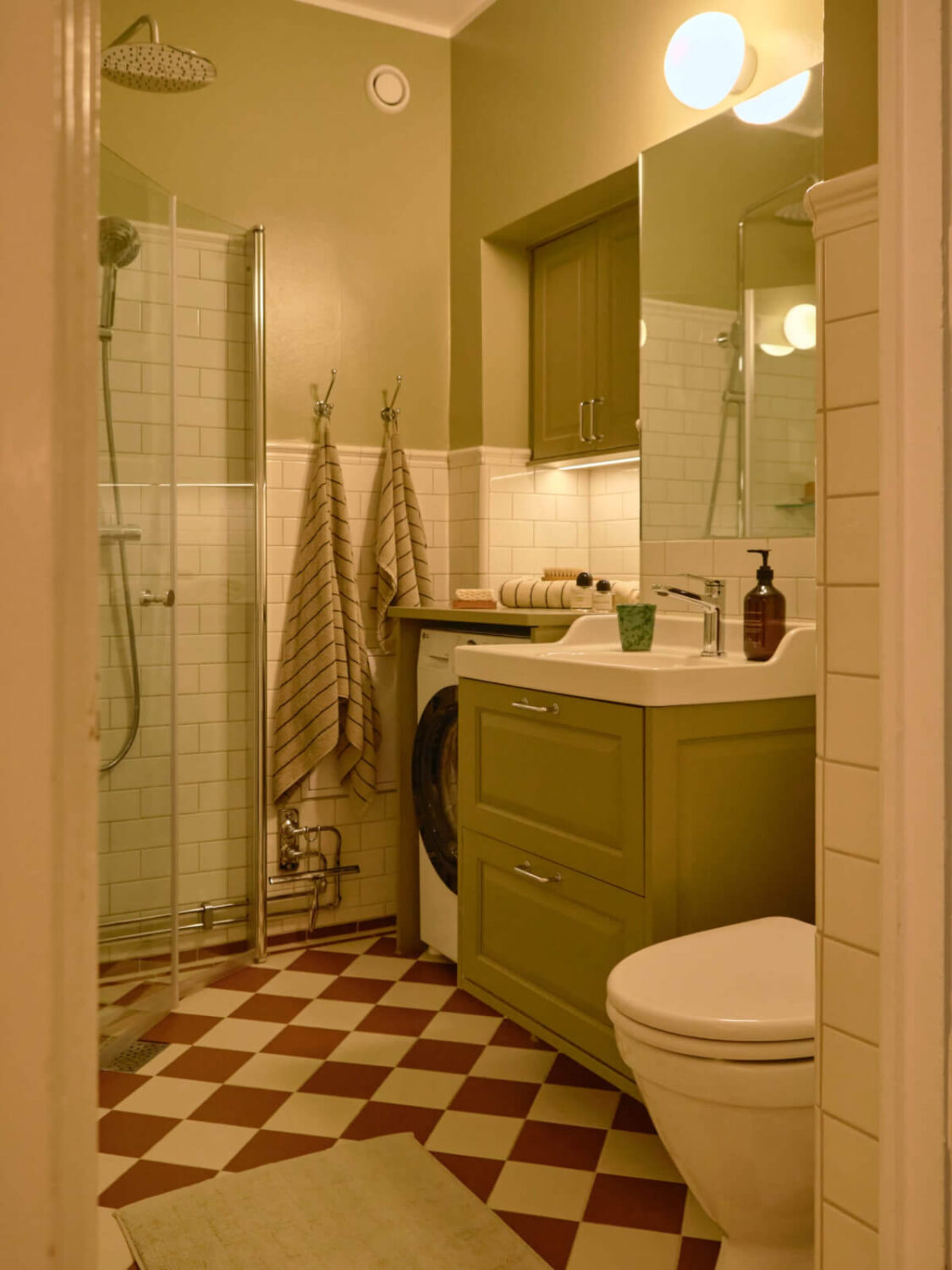 A Beautiful Color Palette and Historic Elements in a Stockholm Apartment 27 green classic bathroom with red and white checkerboard floor