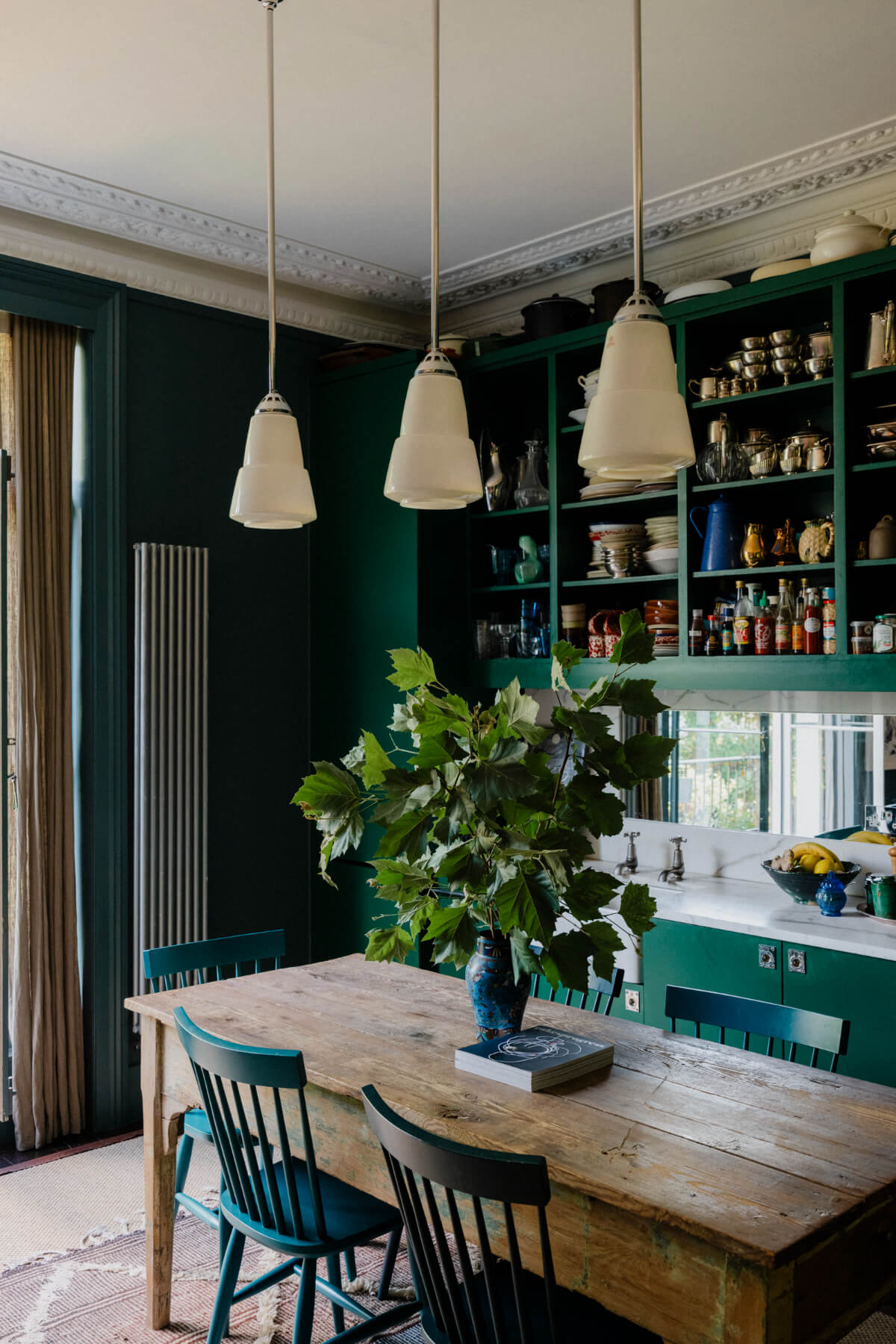 green kitchen with rustic dining table open cabinets and mirror backsplash