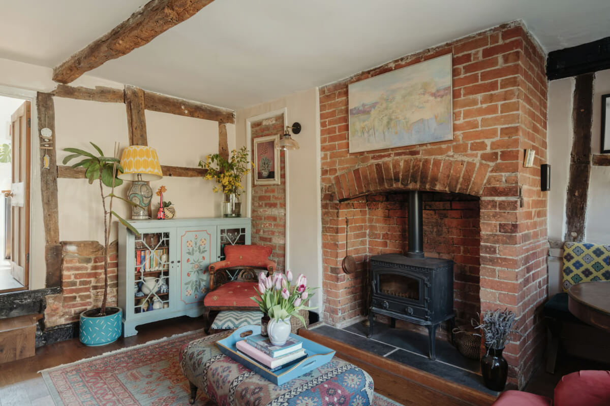A Historic English Cottage Decorated in Pink & Blue Tones 1 historic english cottage living room brick fireplace exposed beams