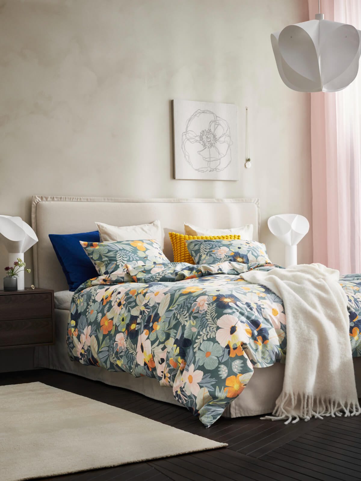 ikea bedroom with floral bedding and neutral textile headboard