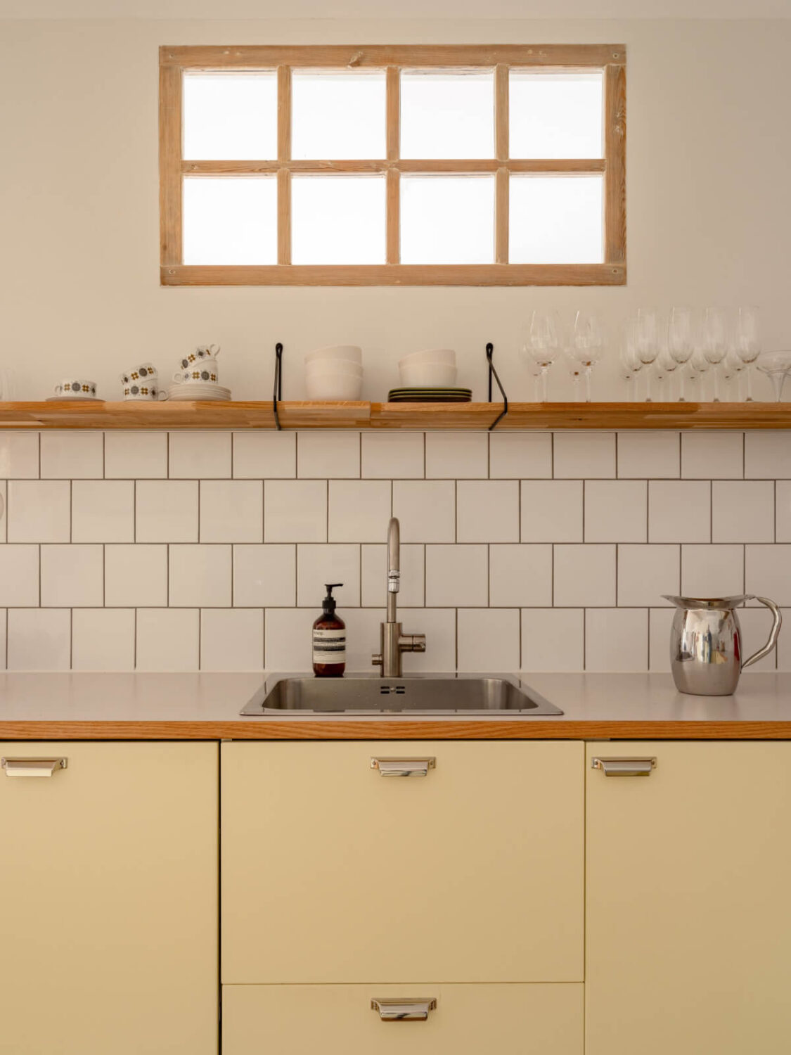 A Light Corner Apartment with a Pale Yellow Kitchen 12 kitchen yellow cabinets white backsplash tiles shelf