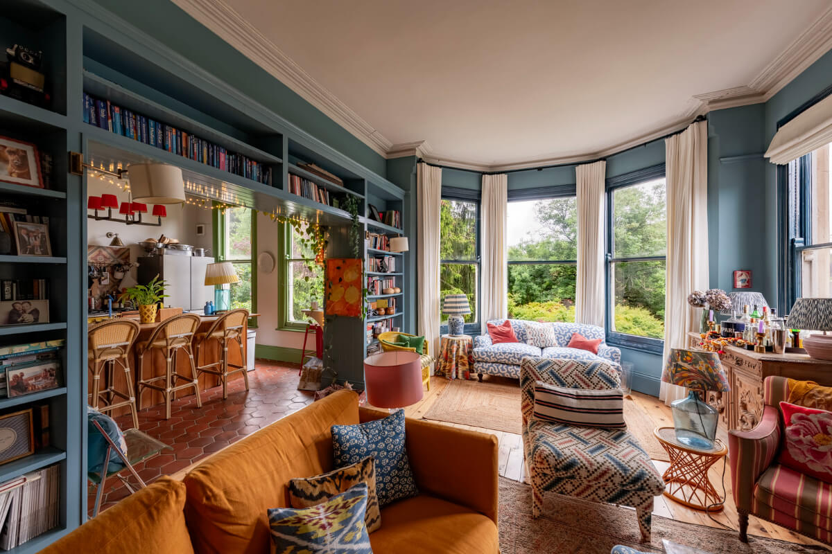 Behr Color of the Year 2026: Hidden Gem 21 open-plan living room kitchen blue walls bookshelves bay window