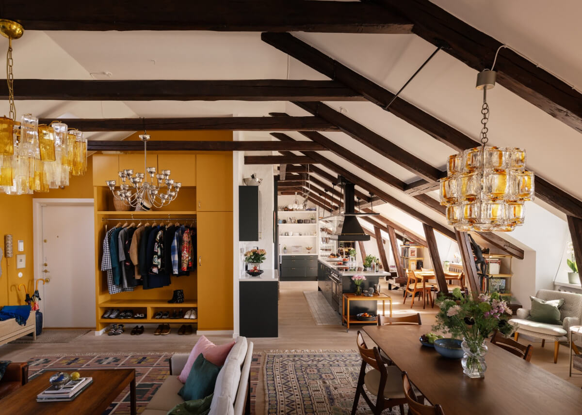 Revisiting a Spectacular Stockholm Penthouse with Exposed Beams 10 open-plan penthouse apartment wooden beams yellow built-in storage