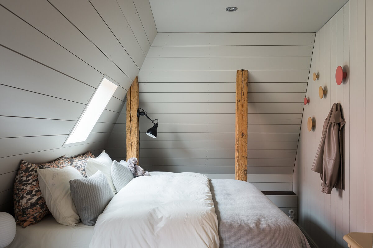 A Stylish Penthouse Apartment with Exposed Beams 26 scandi bedroom slanted ceiling wooden beams