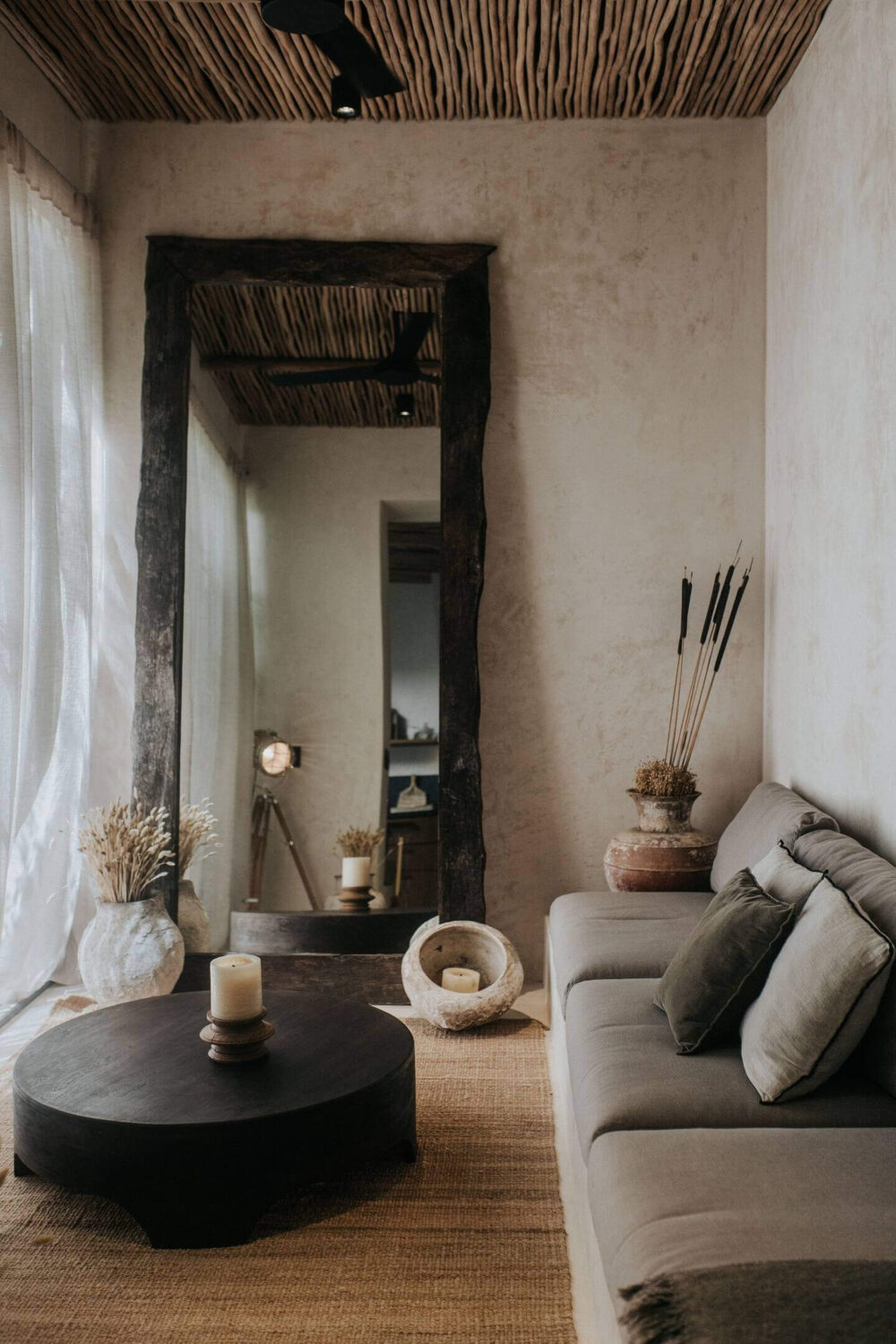Rustic Wooden Elements in a Stylish Tulum Airbnb 7 small-sitting-room-gray-sofa-round-black-coffee-table-large-mirror-wooden-ceiling-nordroom