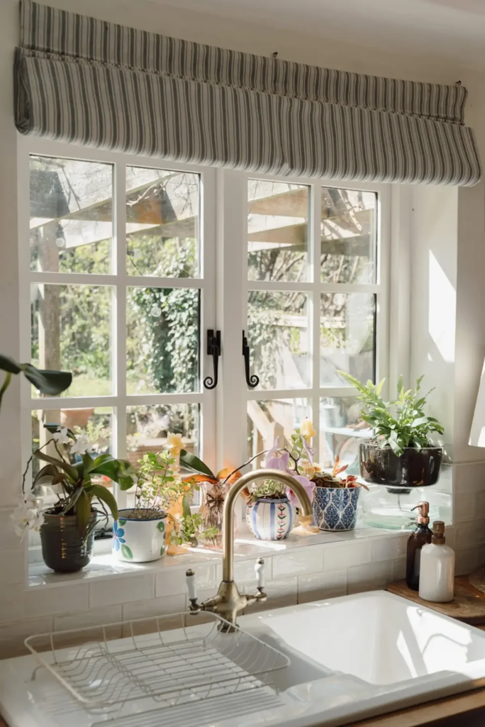 A Historic English Cottage Decorated in Pink & Blue Tones 8 kitchen sink under window striped curtain